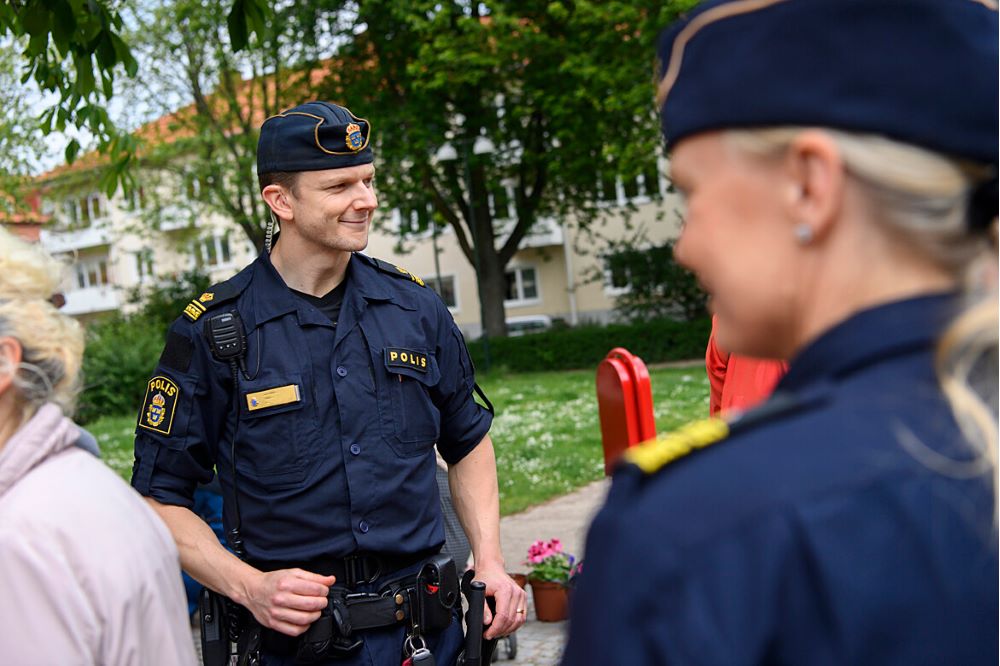 Polis i uniform utomhus i dialog med medborgare.