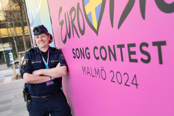 En kvinna i polisuniform står framför en skylt där det står "Eurovision song contest Malmö 2024."